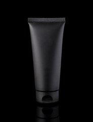 Black cosmetic tube, studio photography of black plastic tube for cream, isolated on black background
