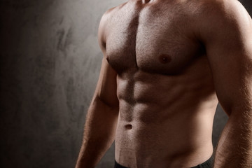 Naklejka premium Close up of sportive man's body over dark background.