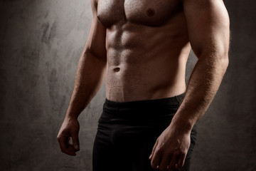Fototapeta premium Close up of sportive man's body over dark background.