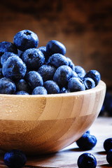 Blueberries in bowl, wooden background, selective focus