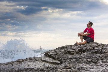 Kroatien, Istrien, Kap Kamenjak, Mann sitzt auf den Felsklippen und schaut entspannt auf die...