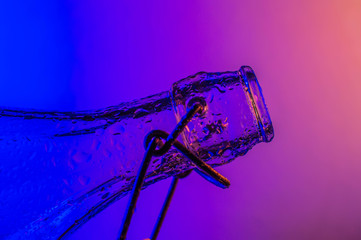 Bottle with droplets with color lights in background