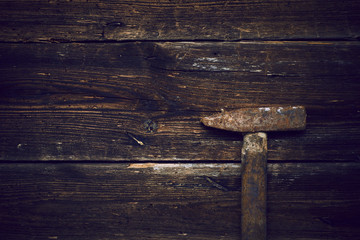 Old steel hammer with wooden handle on the wooden boards background