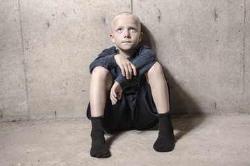 Neglected lonely child leaning at the wall