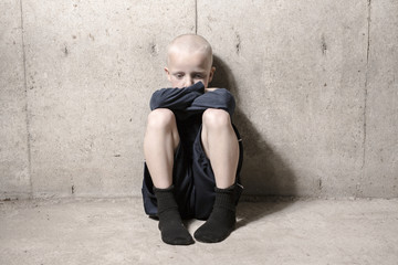 Neglected lonely child leaning at the wall