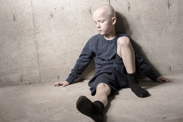 Neglected lonely child leaning at the wall