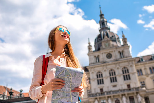 Young woman traveling with map in the central square in Graz old town. Traveling in Austria