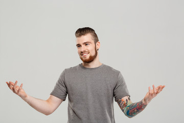 Young handsome man gesturing over grey background. Copy space.