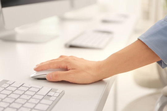 Female hand holding mouse while working on computer
