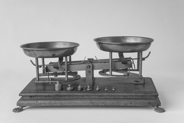 Very old mechanical Weighing Scales on a wooden background in front of the green garden view. Black and white picture