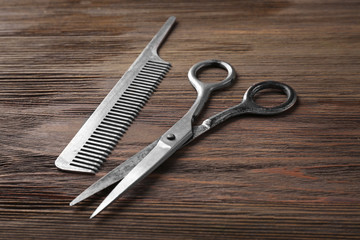 Vintage scissors and comb on wooden background