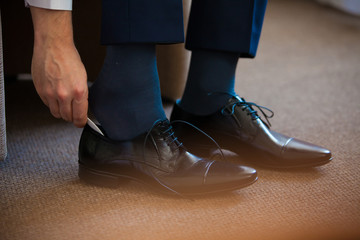 Business man tying shoe laces on the floor. Close-up. - obrazy, fototapety, plakaty
