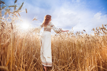 Pretty woman dressed in embroidered blouse in wheat field