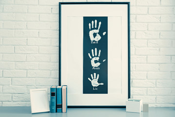 Family hand prints in frame and decor on brick wall background