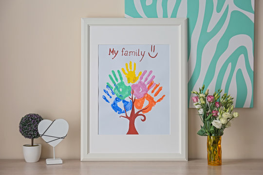Family hand prints in frame and decor on table in room