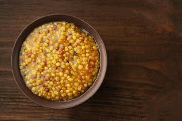 Bowl of French mustard on wooden background