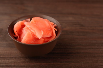 Bowl of marinated ginger on wooden background