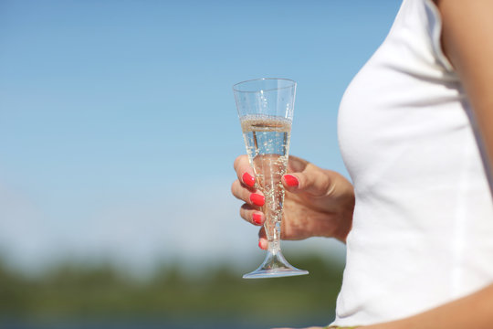 Glass of champagne in hand of a woman on a sunny day