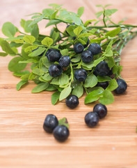 branch of fresh blueberries on wooden surface 