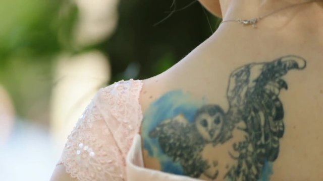 Close-up of woman in pank dress with a owl tattoo on her shoulder.