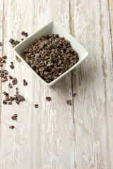 Bowl of Organic Cacao Nibs on a wood plank board