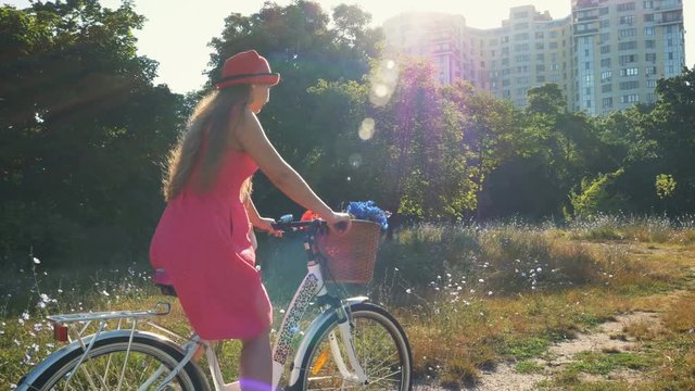 Young attractive girl riding on vintage bike in park at sunset or sunrise