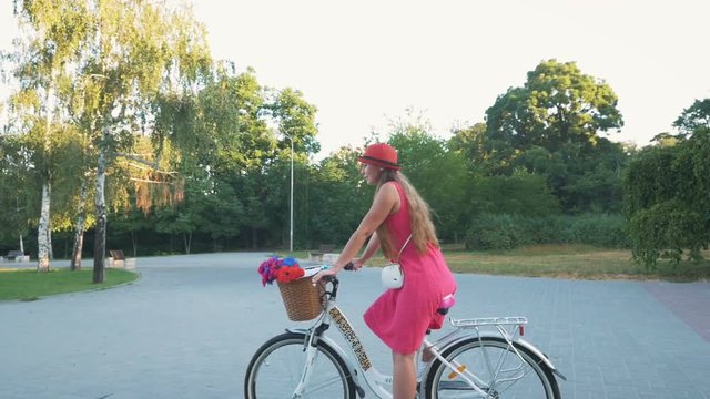 Young attractive girl riding on vintage bike in park at the morning, slow motion