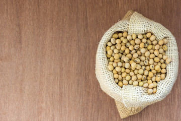 Soybean in hemp sack bag on a wooden background.