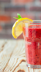 Fresh Fruit Smoothie berry. A glass of red smoothie with orange and mint on a wooden table. smoothie concept