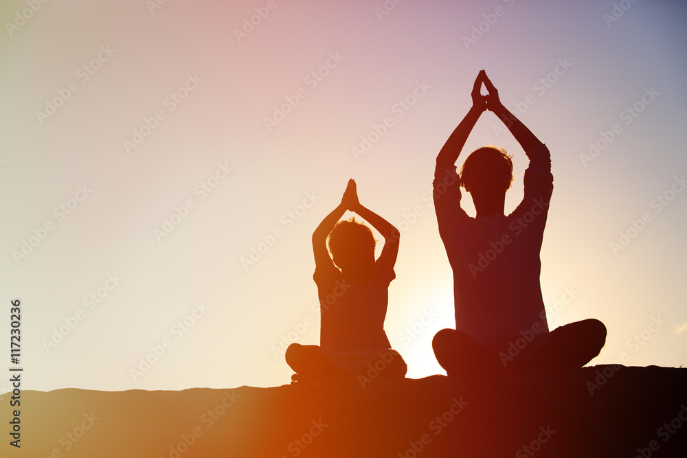 Poster father and son doing yoga at sunset