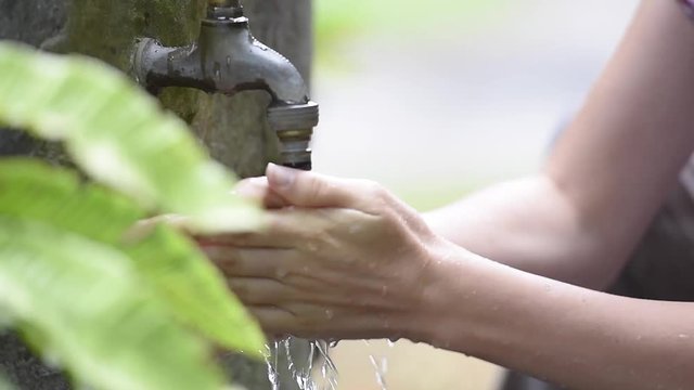 Woman washing her hands from outdoor faucet