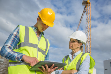 business, building, paperwork and people concept - builder in hardhat with tablett outdoors
