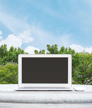 Closeup computer notebook with mouse on cement desk in the park with beautiful blue sky space background in work concept at the outdoor