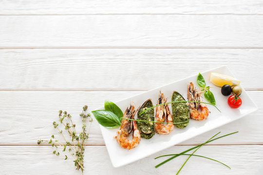 Delicious seafood mix on white wooden background, copyspace. Tasty mediterranean meal with shrimps and mussels, free space for text, restaurant serving