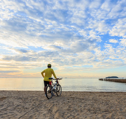 Fototapeta premium Cyclist with bicycle at the sunrise beach