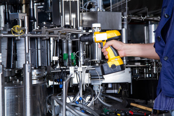 skilled worker while fixing a bottling plant during maintenance work