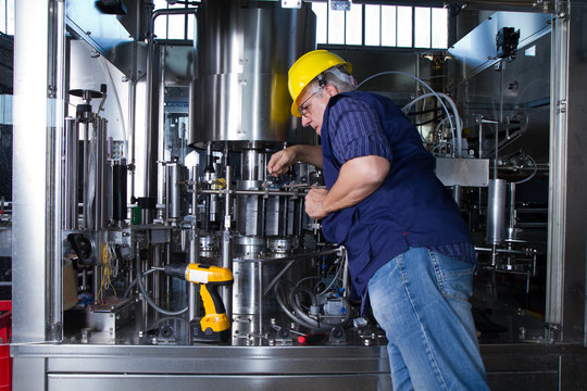 skilled worker while fixing a bottling plant during maintenance work
