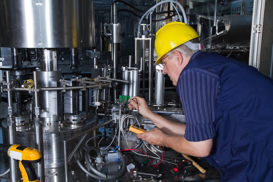 skilled worker while fixing a bottling plant during maintenance work