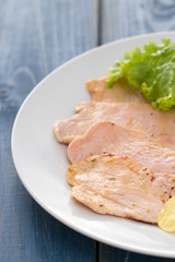 fried meat with potato chips and fresh salad on white dish on blue wooden background
