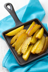 fried potato on black frying pan and blue napkin