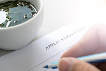 teacup and hand with pen over application form
