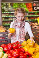 Portrait of beautiful young woman choosing vegetables in grocery