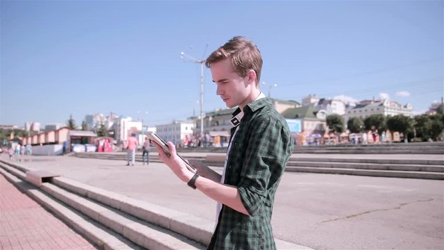 Young tourist man using map on his tablet walking in the city. HD.