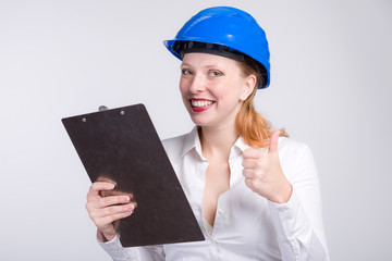 Junge Ingeneurin mit Schutzhelm zeigt Daumen hoch