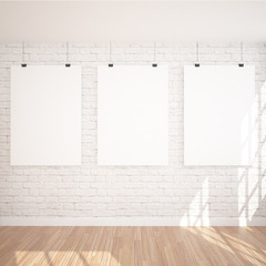 3 Hanging Poster Mock UP In Contemporary Exhibition Interior Space With Floor Lamp. White bricks and wooden floor planks. Perfect Background To Present Your Designs And Photos.