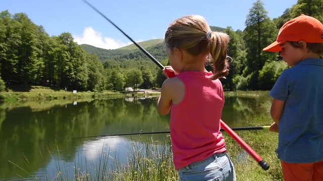 Kids fishing by mountain lake in summer