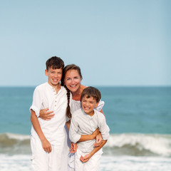 Portrait of a cheerful, happy mother and sons on beach