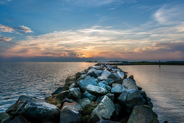 Naklejka premium Sunset over a rock jetty on the Chesapeake Bay