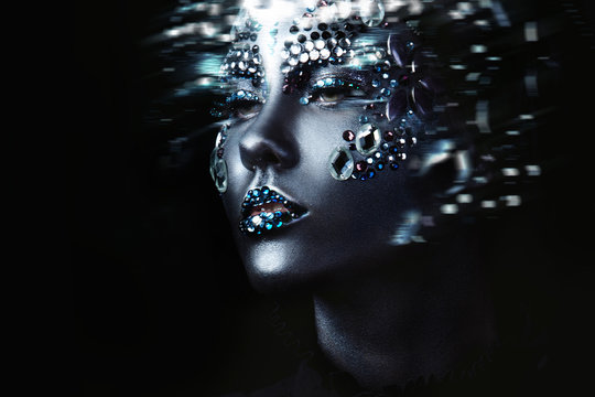 Young beautiful girl in black makeup with rhinestone, dark background, motion effect