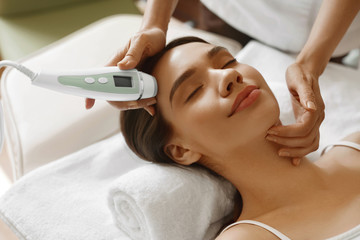 Naklejka premium Skin Care. Women Analyzing Facial Skin With Analyzer. Beauty